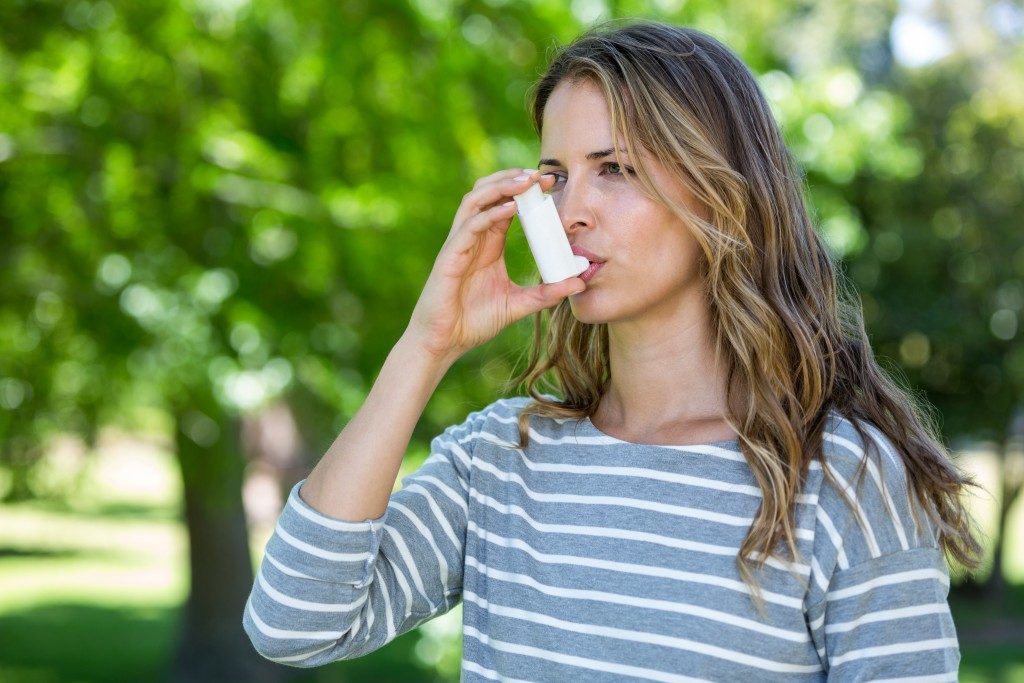 woman using inhaler outdoors due to asthma