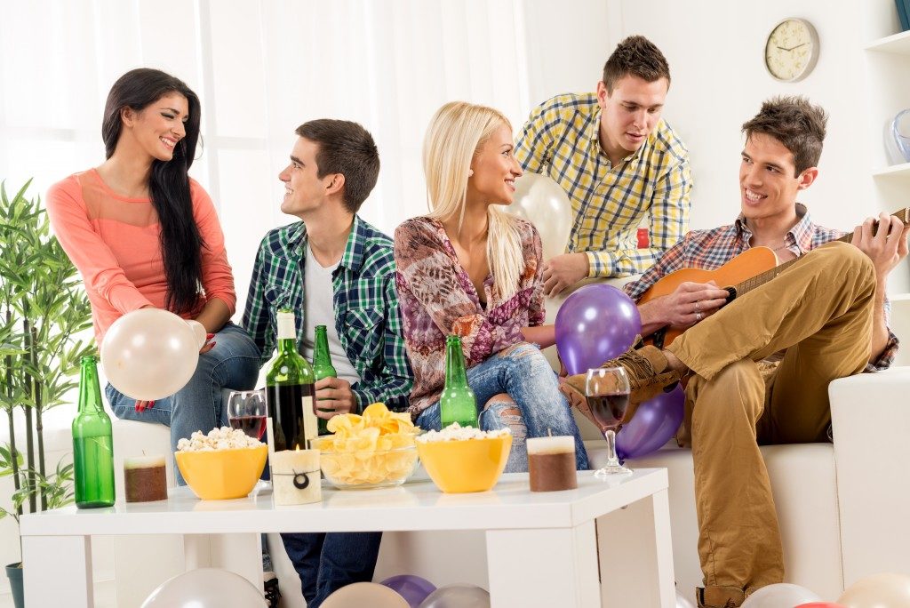 A small group of young people hang out at the house party,