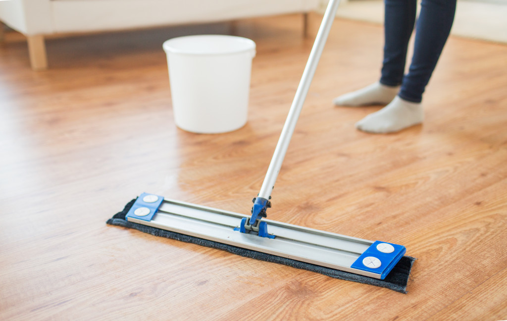 close up photo of woman legs with mop cleaning floor at hom