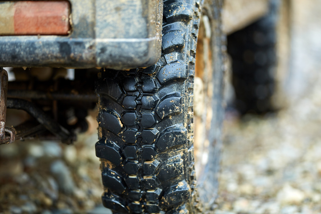A clsoe-up of a 4x4 truck's off-road tires caked with mud after going through a dirt trail