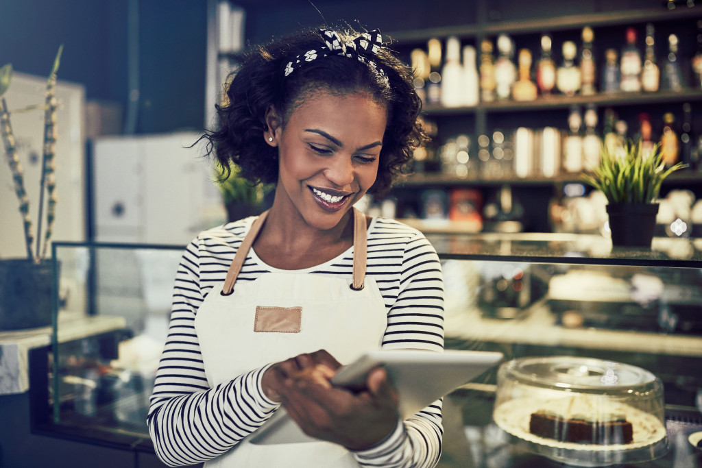 A black woman using a digital tablet while managing her cafe